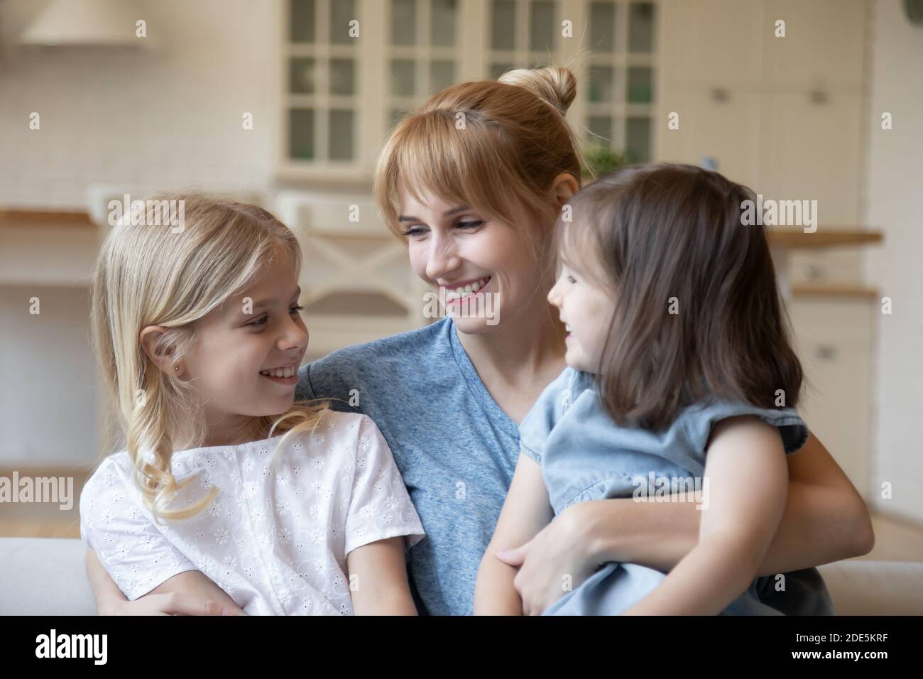Une mère pleine de sourires et aimante embrassant deux petites filles Banque D'Images