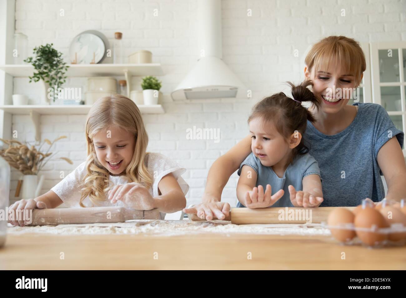 Bonne mère et petites filles cuisinant ensemble, à l'aide d'un rouleau Banque D'Images