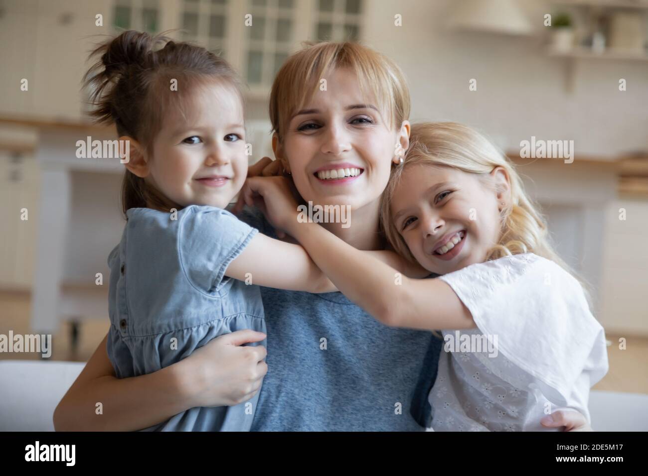 Portrait de tête souriant jeune mère embrassant deux filles Banque D'Images