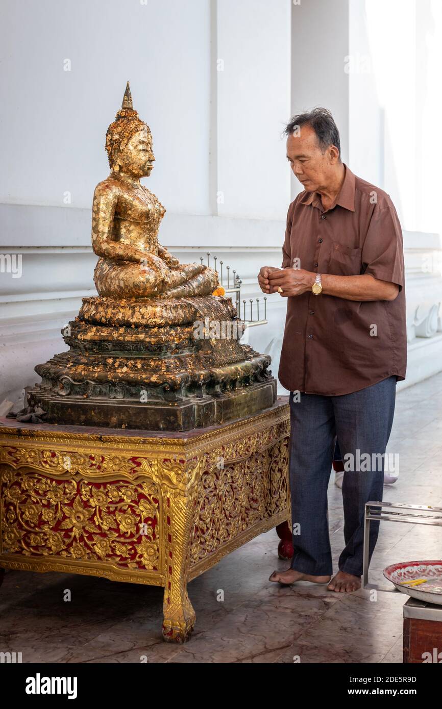 Thaïlande; Jan 2020: L'homme bouddhiste colle des feuilles d'or sur la statue de Bouddha doré, l'homme priant dans la pose reconnaissante. Bouddha assis en position lotus. Wihan P. Banque D'Images