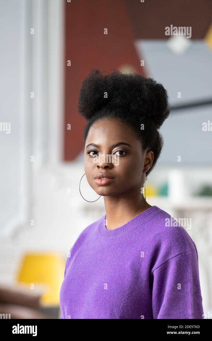 Portrait d'une jeune femme afro-américaine mignonne avec une coiffure frite la coiffure afro porte un chandail violet regardant l'appareil photo. Banque D'Images