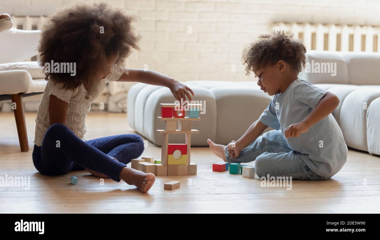 Petite sœur africaine et frère jouant des cubes colorés sur le sol Banque D'Images