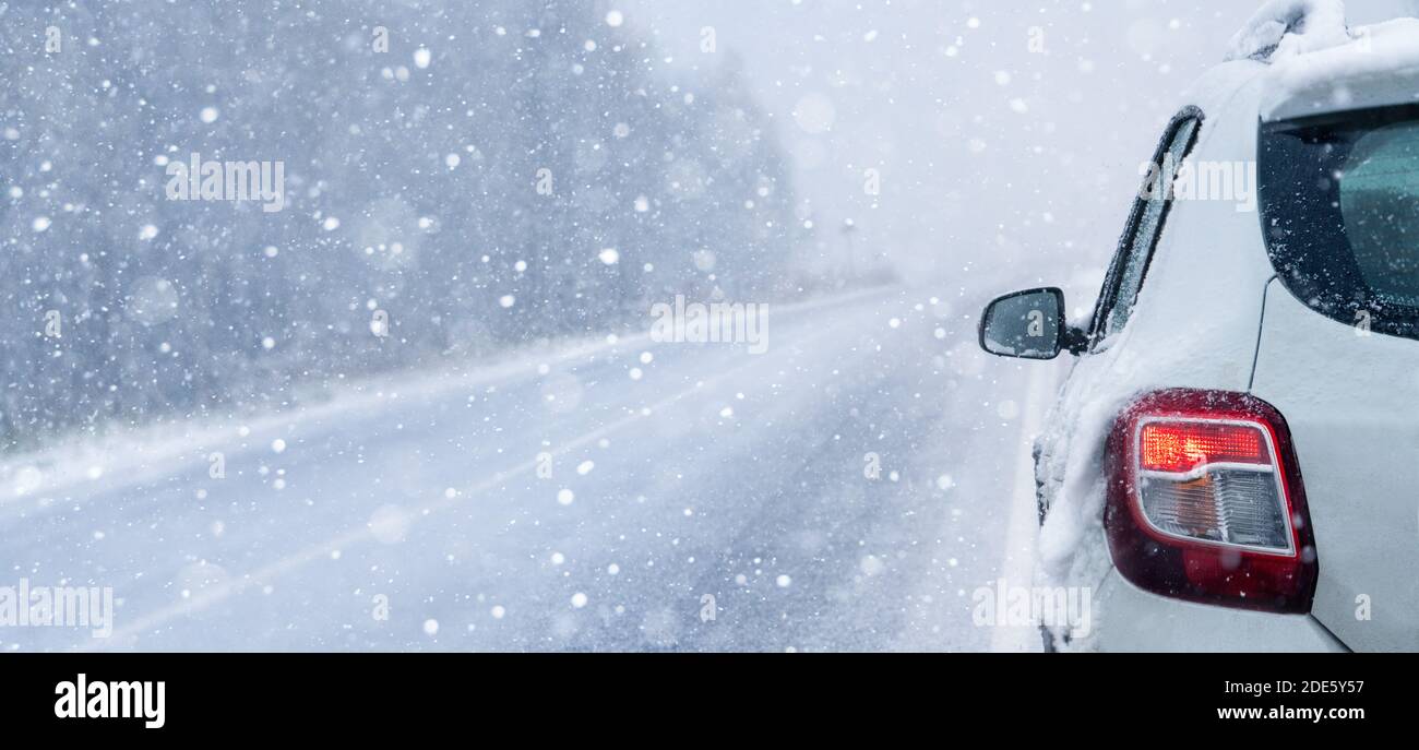 Voiture blanche sur une route d'hiver par une forêt couverte de neige. Banque D'Images