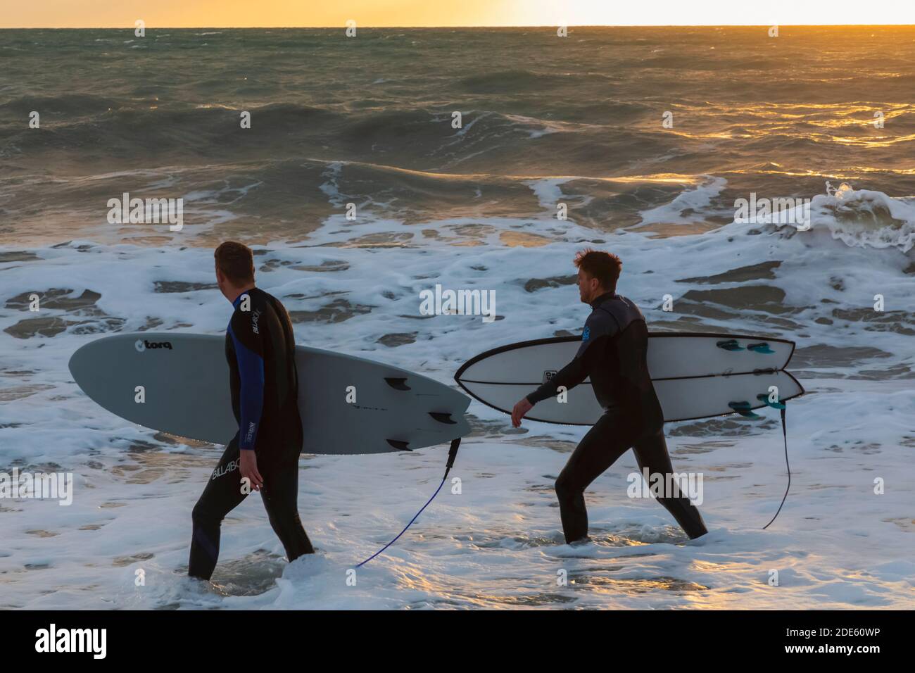 Angleterre, East Sussex, Eastbourne, Birling Gap, Seven Sisters Cliffs and Beach, Two Male Surfers Walking on Beach transportant des planches de surf Banque D'Images