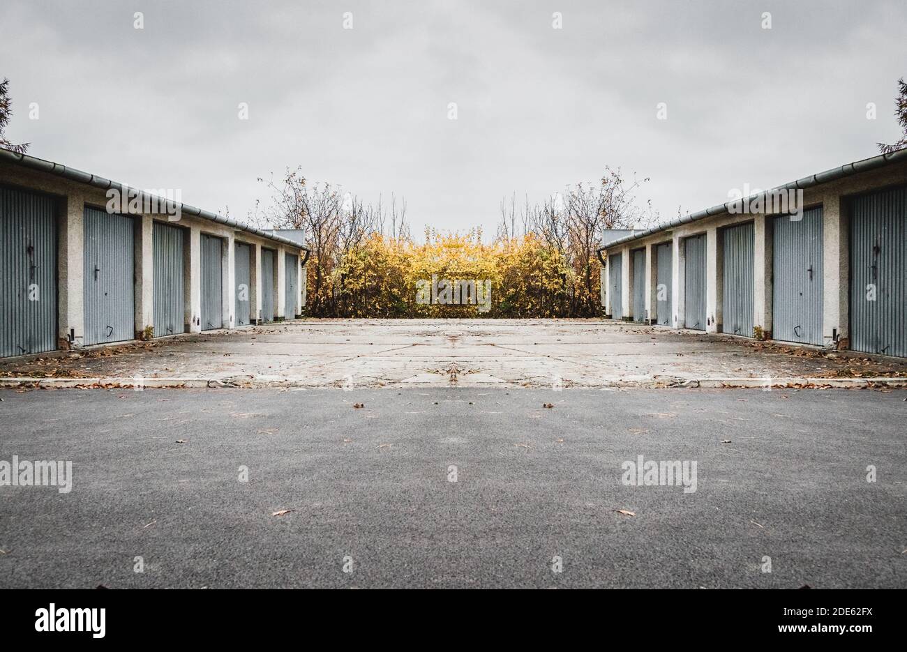 Parking et garages sur les côtés avec de la végétation derrière la clôture par jour nuageux Banque D'Images