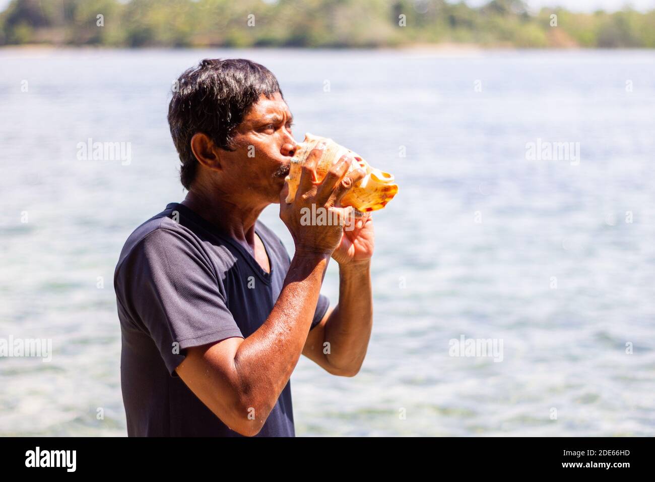 Un homme Tausug utilisant une corne traditionnelle de coquilles de conque à Sulu, Philippines Banque D'Images