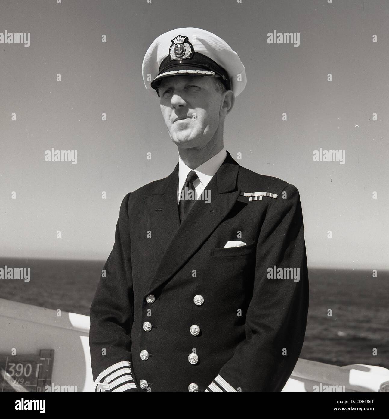 Années 1950, historique, portrait d'un capitaine de navire à vapeur de château de l'Union debout à l'extérieur sur le pont de son navire en mer. Banque D'Images