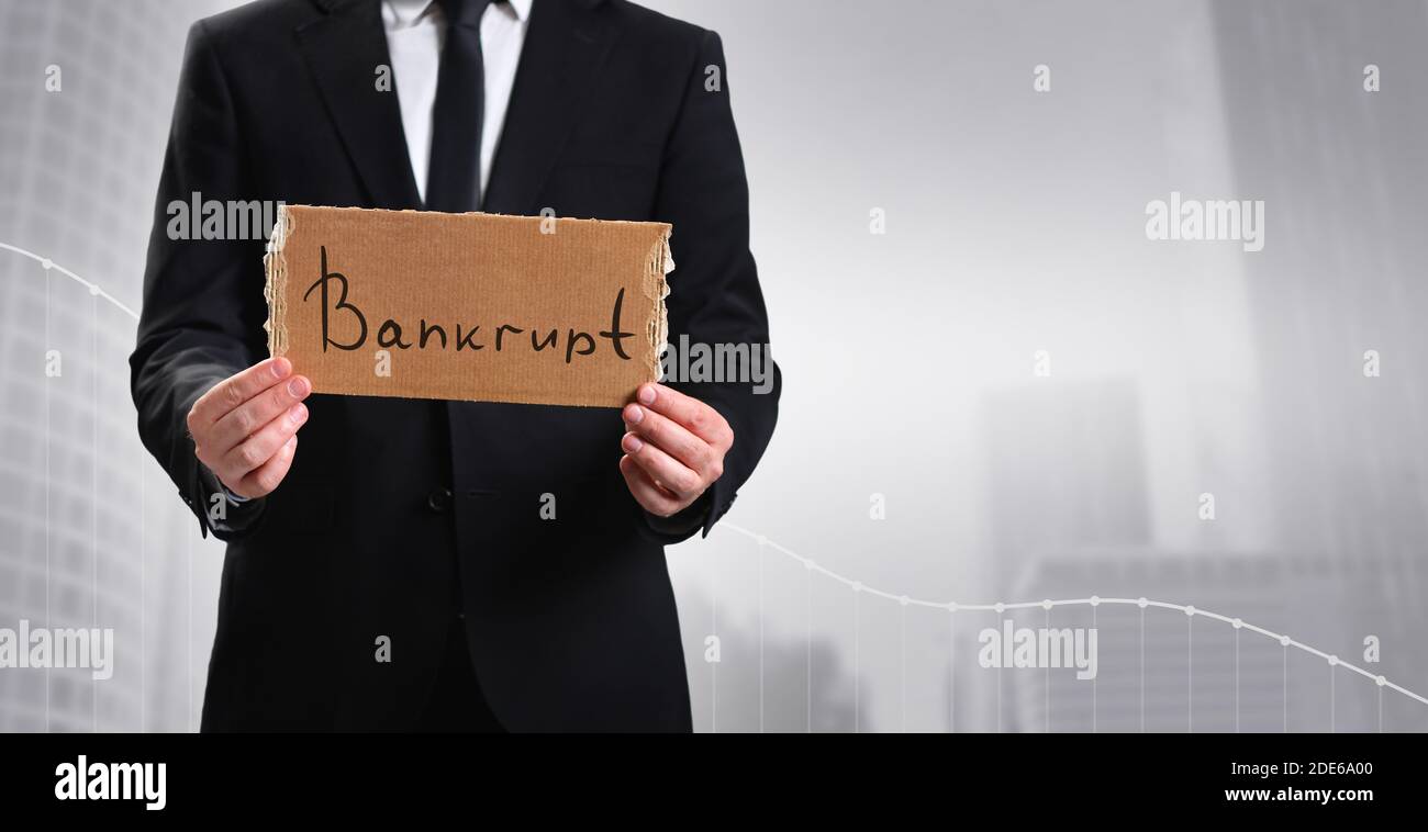Homme d'affaires affichant un message de faillite sur fond gris Banque D'Images