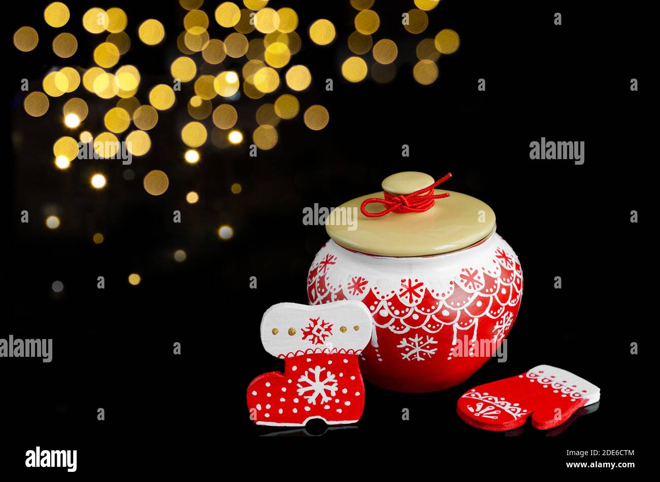 Ensemble de Noël avec un pot et des ornements en bois en rouge, sur fond noir avec bokeh Banque D'Images