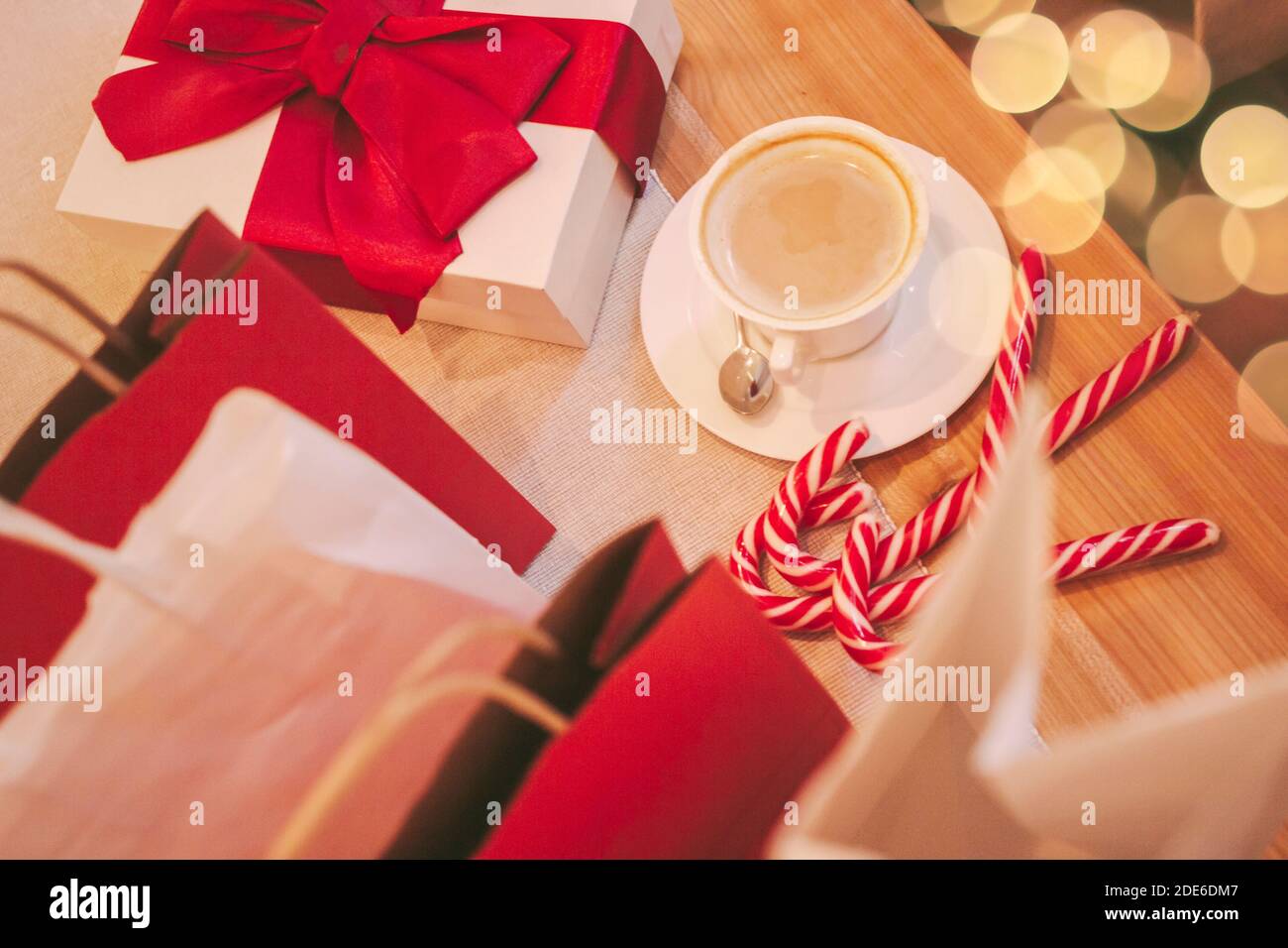 Vue de dessus des boîtes-cadeaux de fête de Noël et des sacs en papier sur une table en bois dans le café. Présente avec ruban rouge, café, bonbons de canne, sacs à provisions. Banque D'Images