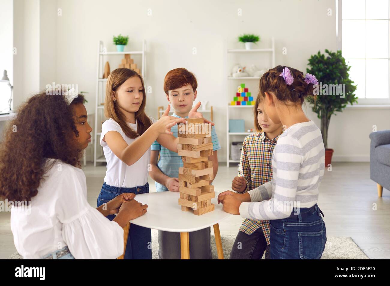 Course mixte enfants amis jouant à la pyramide de construction de détails en bois ensemble Banque D'Images