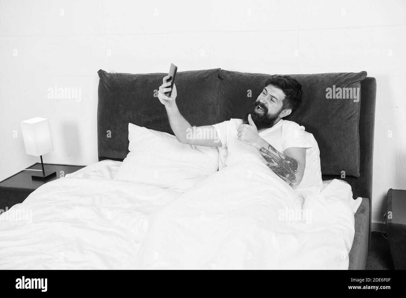 Essayez les appels vidéo. Bonne taille pour la caméra vidéo. Homme barbu passer un appel vidéo au lit. Visioconférence. Conservation de vlog. Vlogging vivant. Télévision Web. Communication en ligne. La vie moderne. Banque D'Images