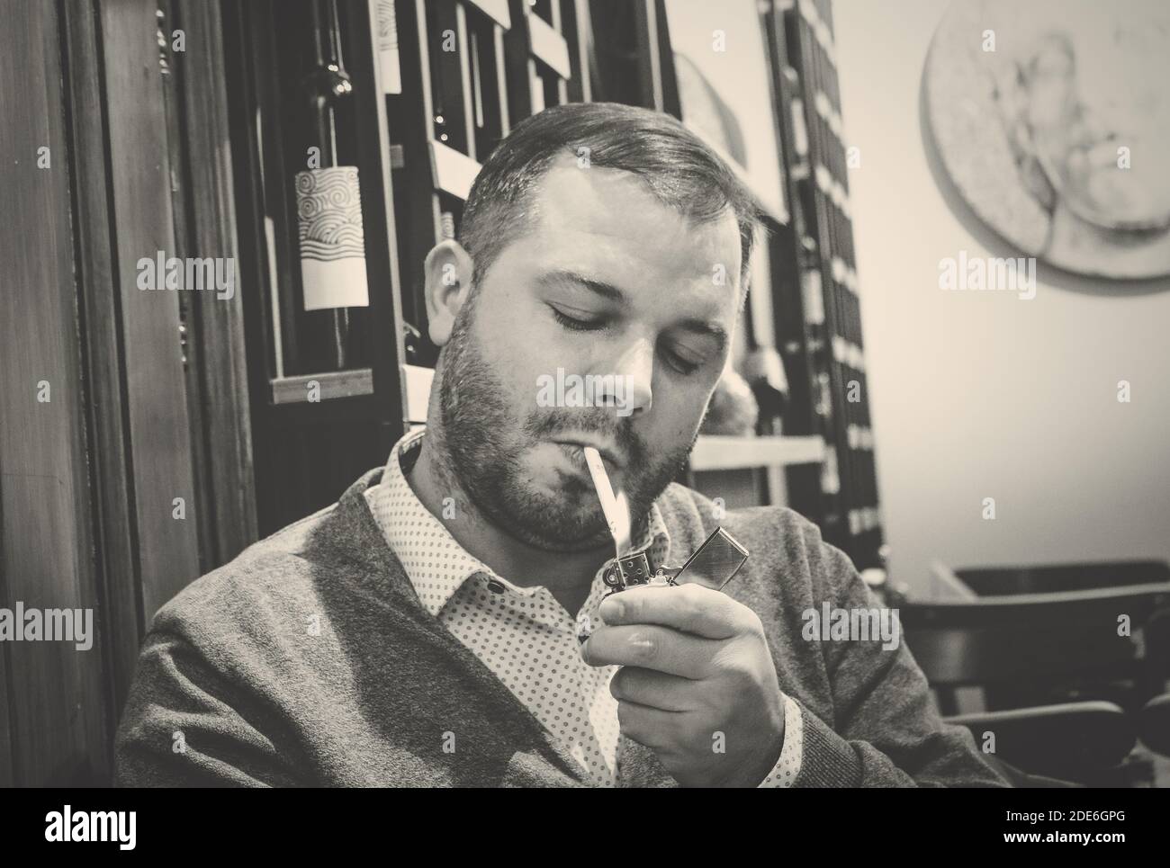 Portrait noir et blanc d'un homme qui allume une cigarette Banque D'Images