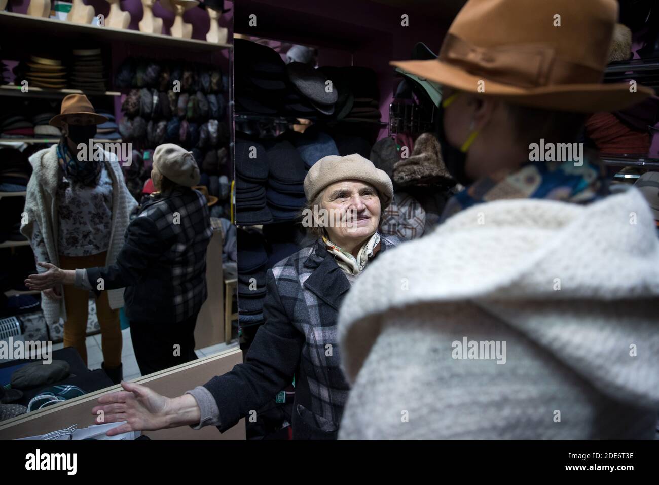 Le propriétaire du magasin aide un client à essayer un chapeau.pendant les  deux derniers jours, un petit magasin de chapeau regorge de clients, c'est  ainsi que les gens de Cracovie ont décidé