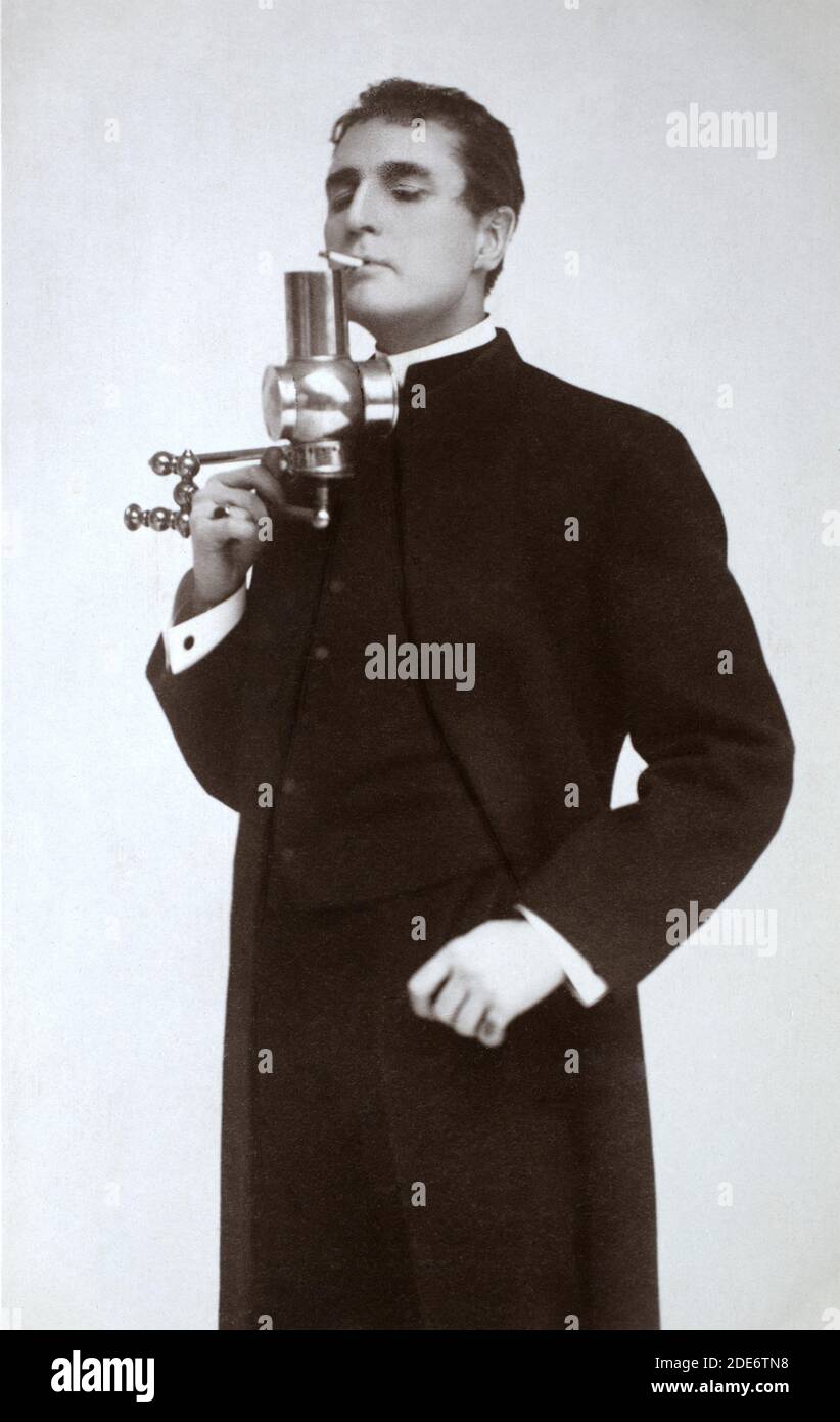 Le célèbre acteur, directeur, dramaturge et scénariste américain William Gillette (1853 – 1937) a posé en costume Sherlock Holmes, éclairant une cigarette d'une lampe. Prise d'une carte postale photographique de l'époque. Banque D'Images