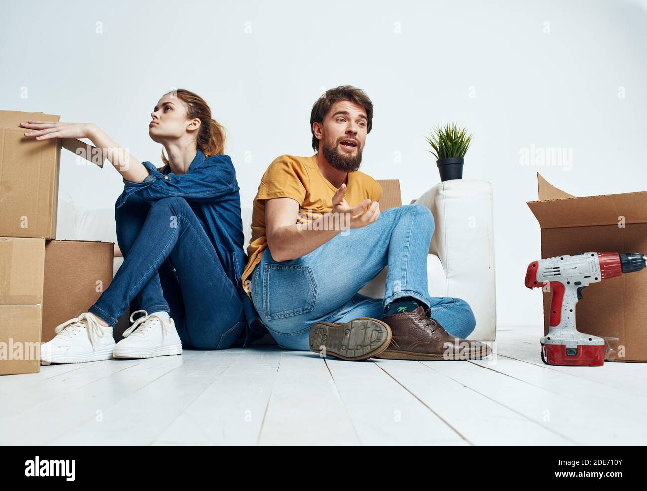 homme et femme assis sur le sol avec leur dos à d'autres travaux de rénovation déplacer une fleur dans un pot Banque D'Images