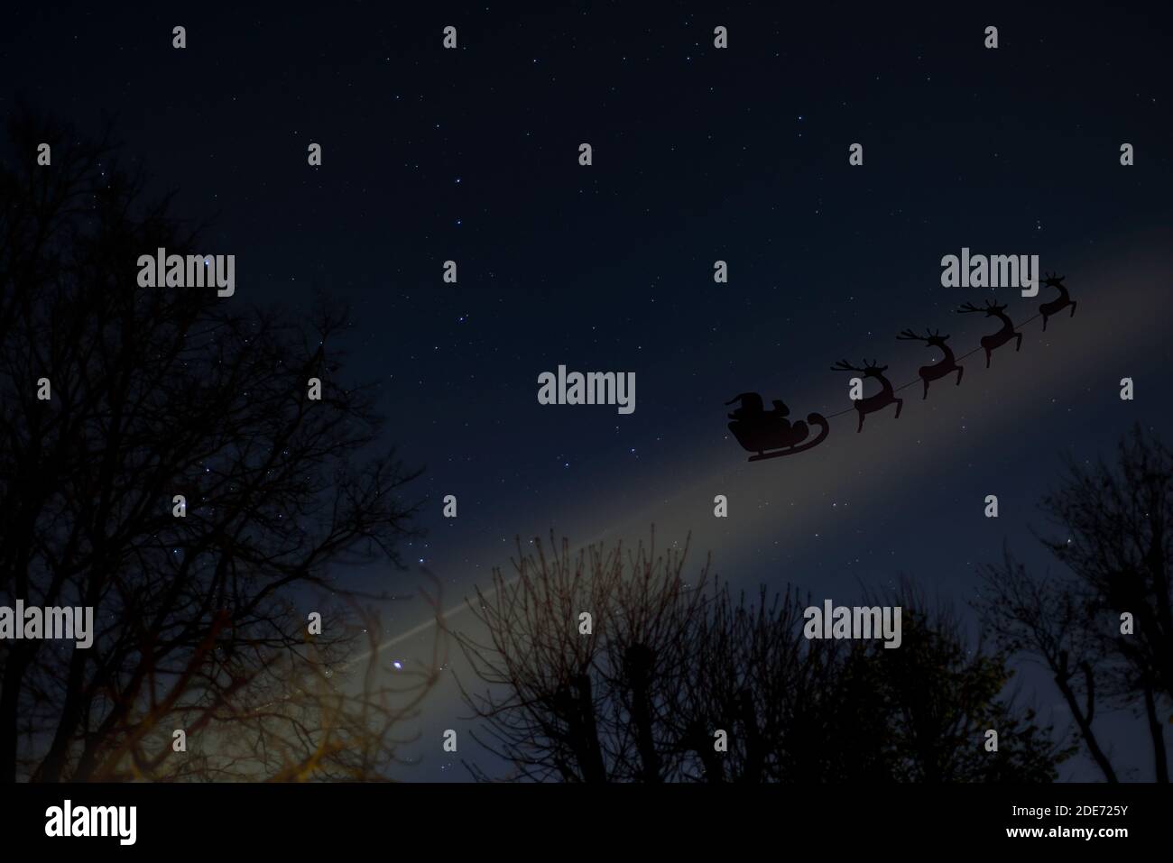 Santa traîneau volant avec renne dans un ciel d'hiver avec étoiles et sentier de lumière magique Banque D'Images