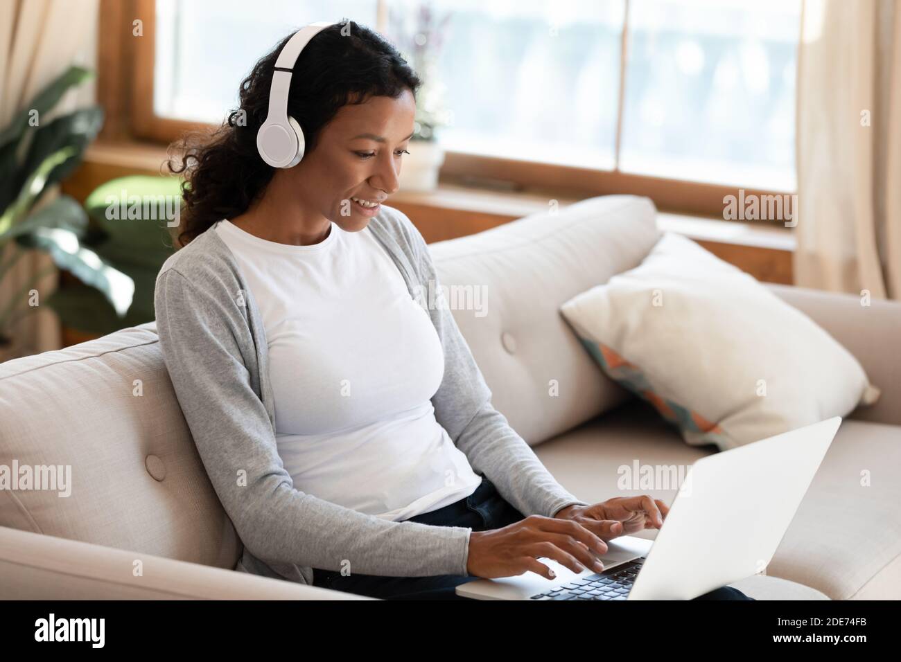 Une femme biraciale dans un casque travaille sur un ordinateur portable Banque D'Images