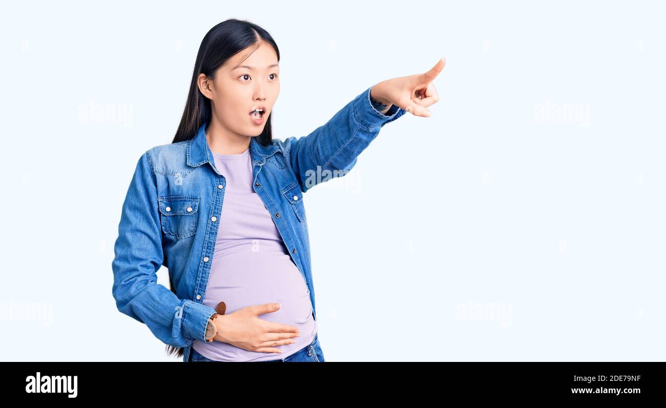 Jeune Belle Femme Chinoise Enceinte S Attendant A Un Bebe Pointant Avec Le Doigt Surpris Devant Bouche Ouverte Expression Stupefaite Quelque Chose Sur Le Front Photo Stock Alamy