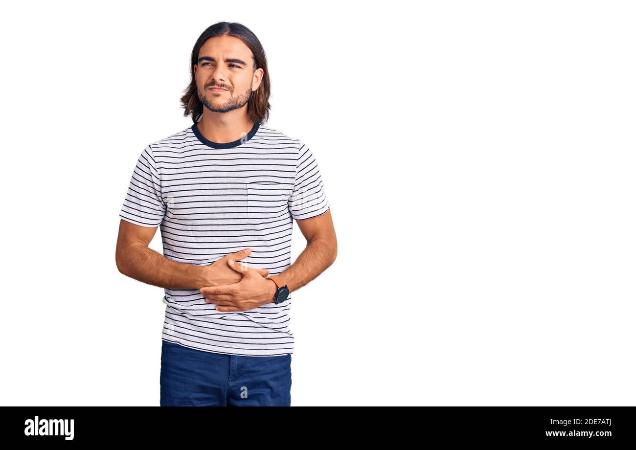 Jeune homme beau portant des vêtements décontractés avec la main sur l'estomac parce que l'indigestion, la maladie douloureuse sentiment malaise. Ache concept. Banque D'Images