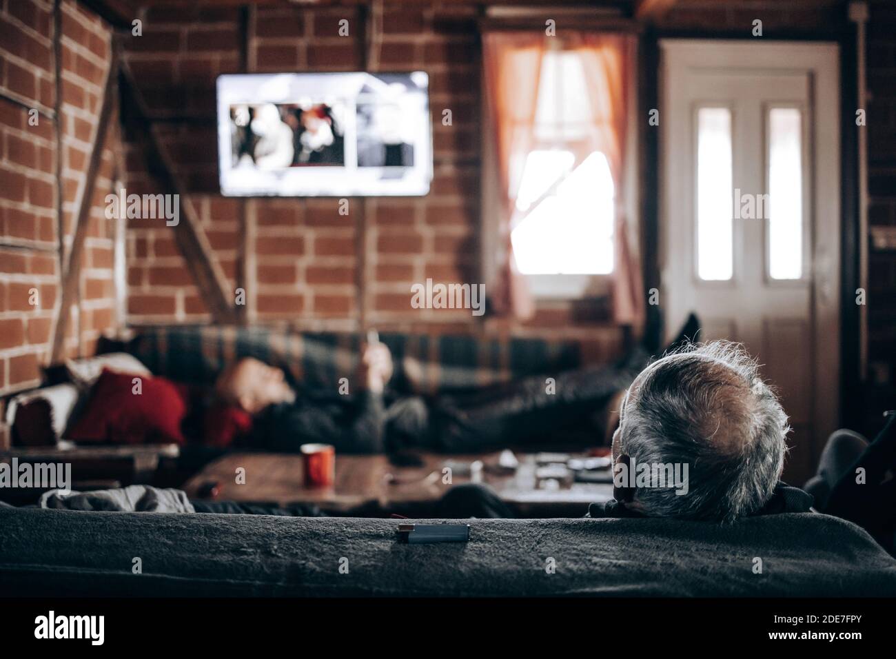 Homme âgé regardant la télévision, assis sur un canapé. Vue arrière Banque D'Images