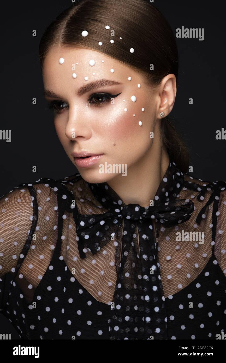 Portrait d'une belle femme dans une robe noire avec perles et maquillage classique. Banque D'Images