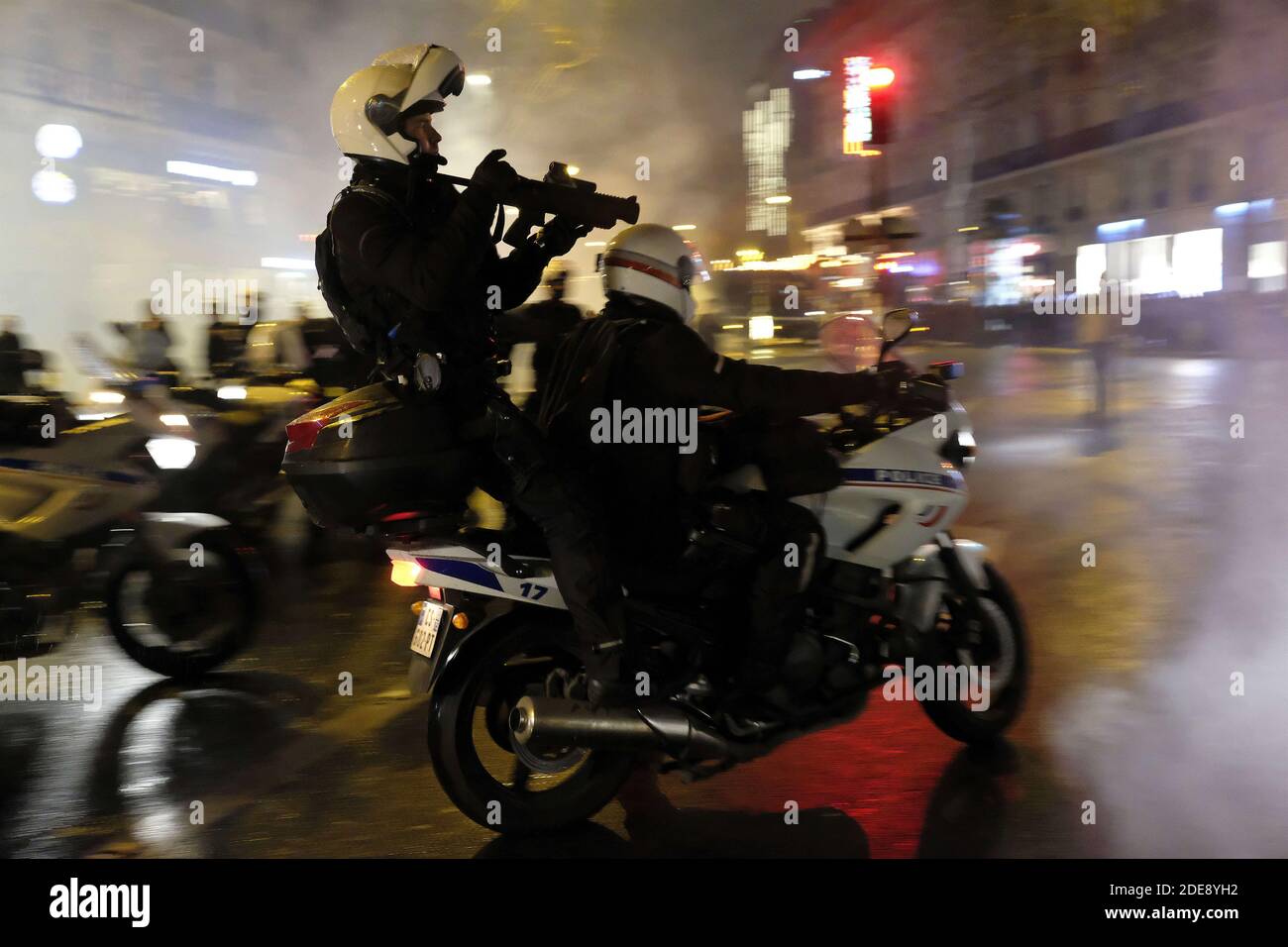 Police anti-émeutes française armée de LBD 40, Flash-ball (armes à balles  en caoutchouc non létales) sur moto visant des manifestants lors d'un  affrontement avec la police anti-émeute française lors d'un affrontement sur