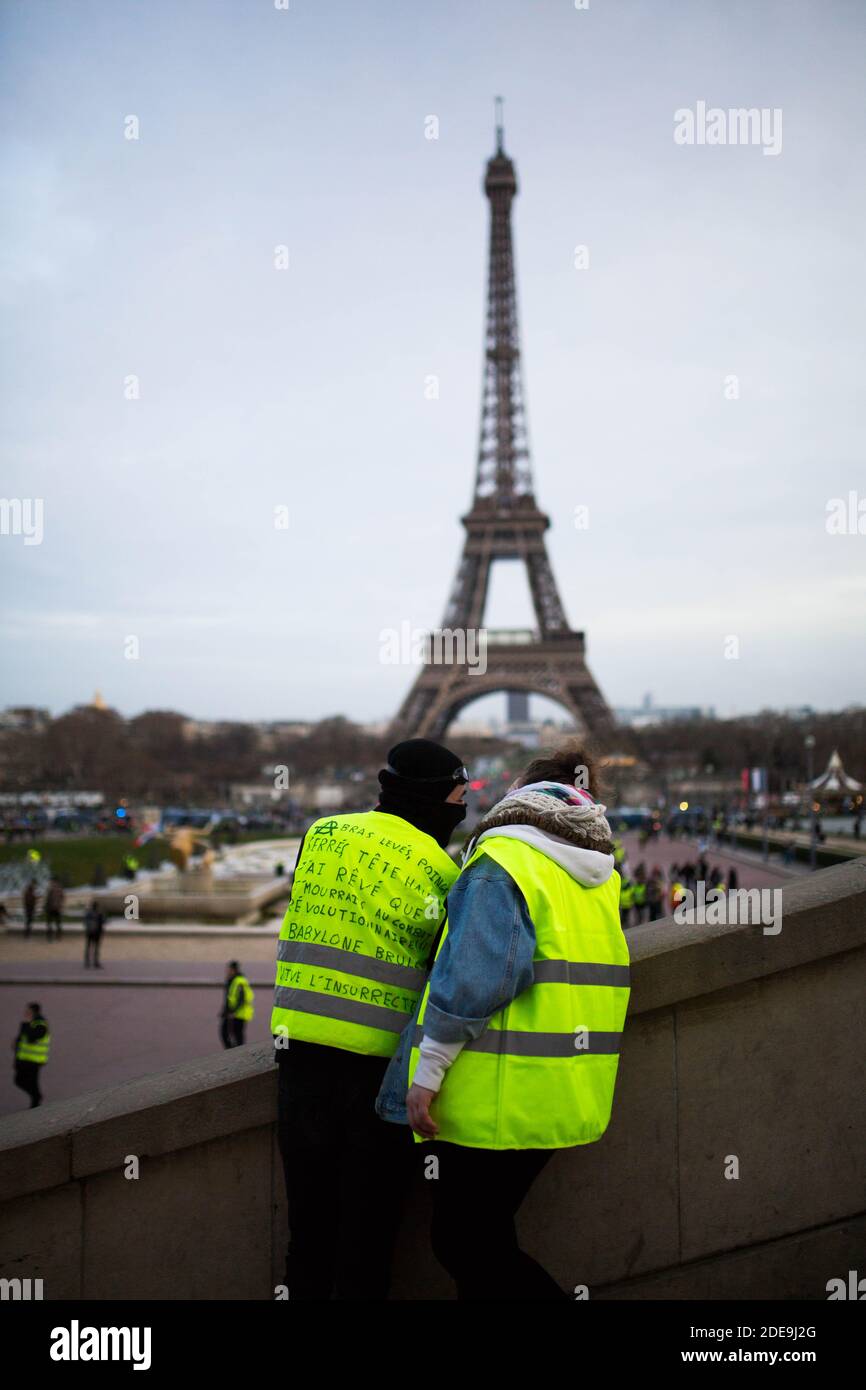 Un couple de manifestants portant un « gilet jaune » se dresse devant la  Tour Eiffel lors d'une manifestation à Paris le 9 février 2019, alors que  les manifestants « gilets jaunes » (