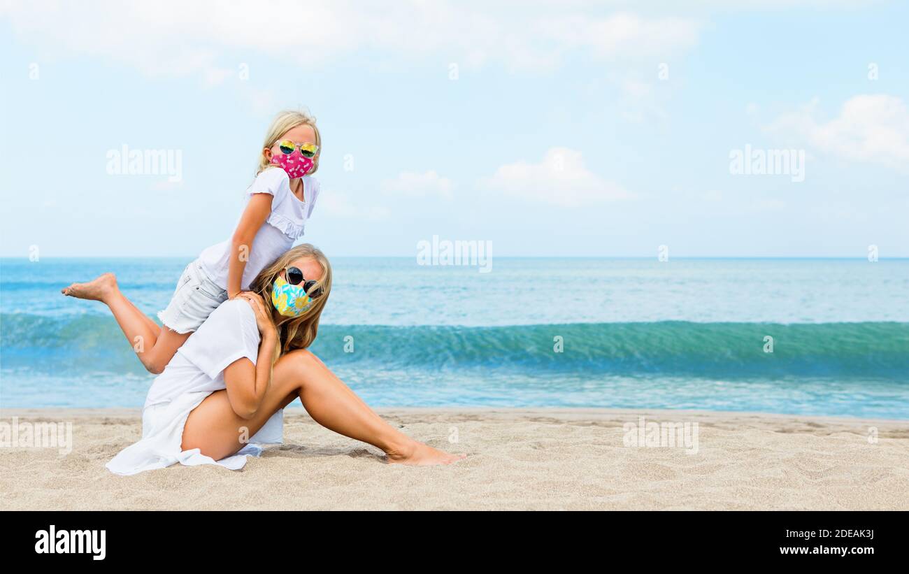 La mère, l'enfant dans les masques de visage ont l'amusement sur la plage de sable de mer. Règles de port de couvre-visage dans les lieux publics. Croisière annulée, excursion due au coronavirus COVID 19 Banque D'Images