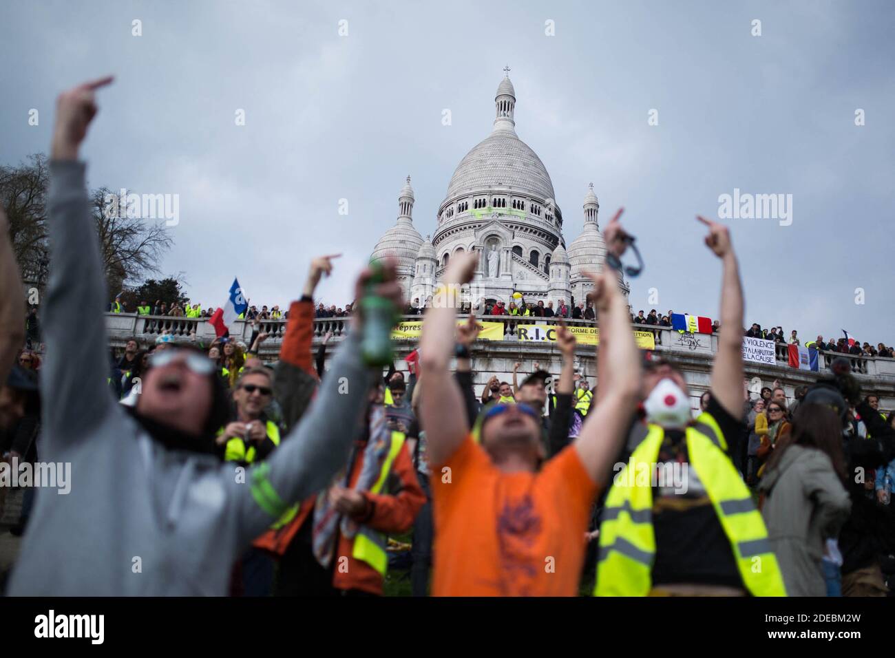 Les manifestants de la Yellow Vest se rassemblent devant la basilique du Sacré-cœur à Montmartre et saluent un doigt un hélicoptère de police, à Paris, le 23 mars 2019, lors d'une manifestation antigouvernementale appelée par le mouvement de la « Yellow Vest » (gilets jaunes). Les manifestants ont de nouveau frappé les rues des villes françaises le 23 mars, pour une 19e semaine consécutive de protestation nationale ( Loi 19 ) contre les politiques du président français et son style de gouvernement descendant, le coût élevé de la vie, les réformes fiscales gouvernementales et pour une plus grande « justice sociale et économique. » photo de Raphael Lafargue/ABACAPRESS.COM Banque D'Images