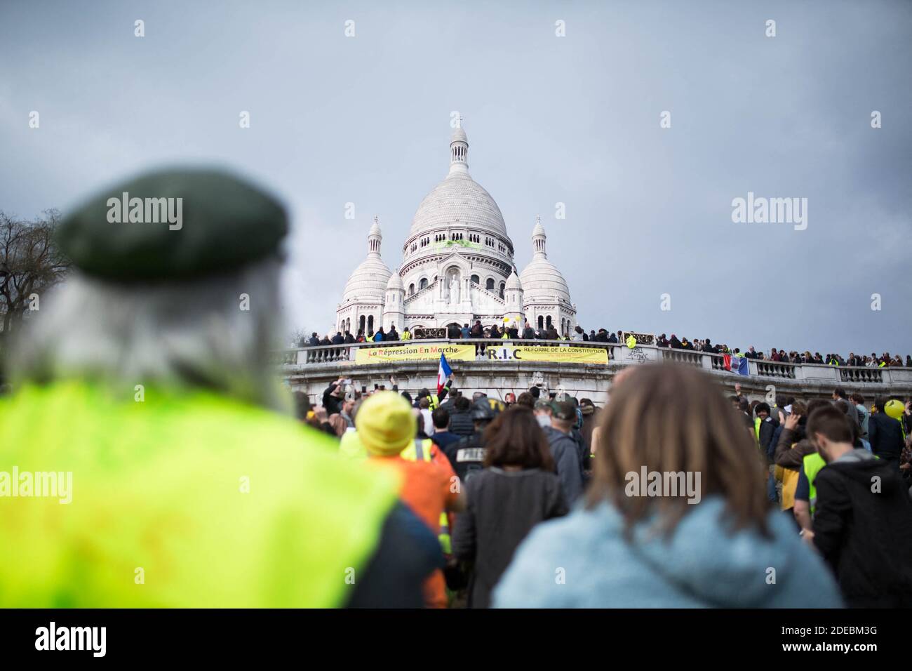 Les manifestants de la Yellow Vest se rassemblent devant la basilique du Sacré-cœur à Montmartre et regardent les manifestants qui fixent un panneau jaune sur le Sacré-cœur, à Paris, le 23 mars 2019, lors d'une manifestation antigouvernementale organisée par le mouvement de la « Yellow Vest » (gilets jaunes). Les manifestants ont de nouveau frappé les rues des villes françaises le 23 mars, pour une 19e semaine consécutive de protestation nationale ( Loi 19 ) contre les politiques du président français et son style de gouvernement descendant, le coût élevé de la vie, les réformes fiscales gouvernementales et pour une plus grande « justice sociale et économique. » photo de Raphael Lafargue/ABACAPRESS.COM Banque D'Images