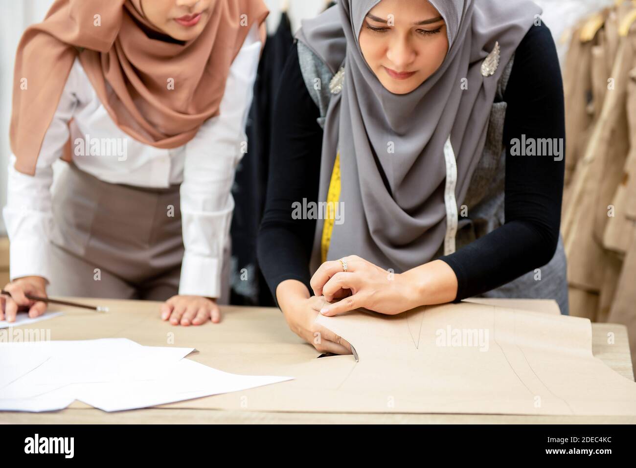 Femme musulmane designer de mode travaillant avec son collègue de découpage motif de vêtements dans une boutique sur mesure Banque D'Images