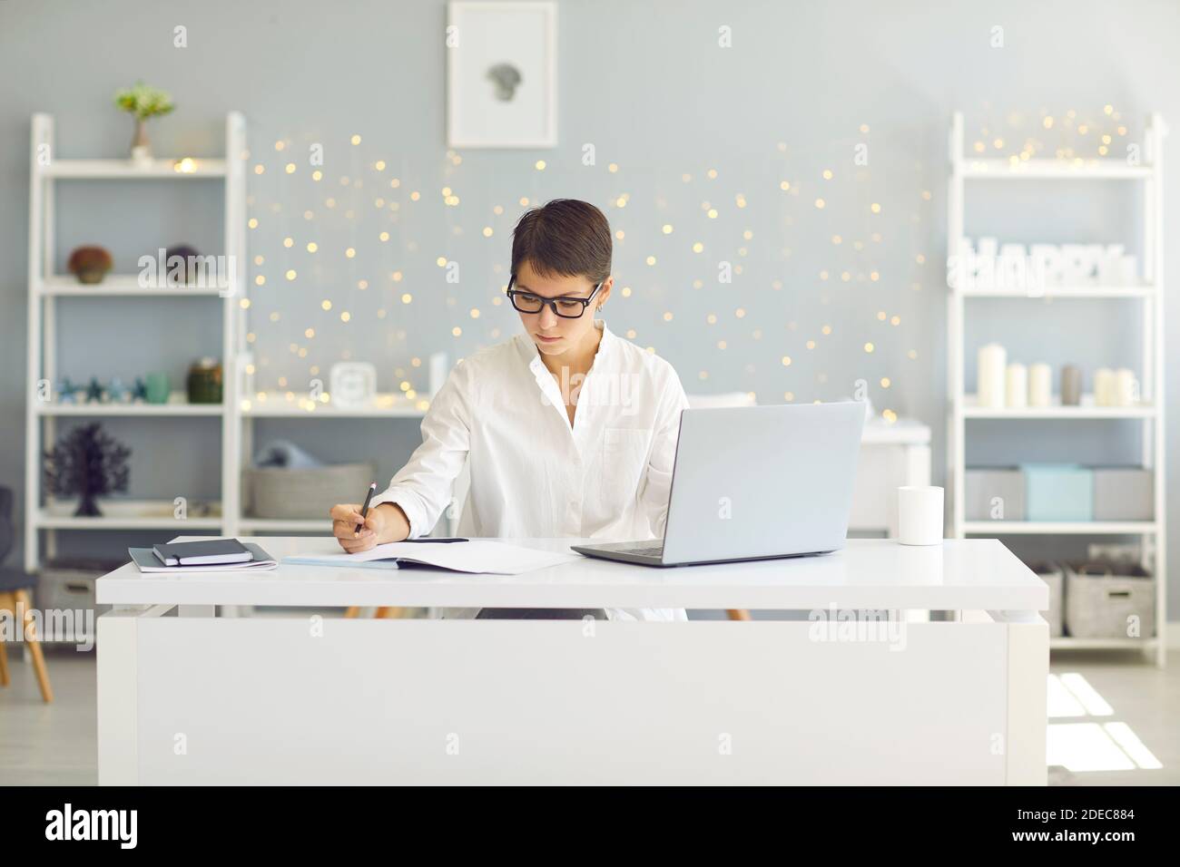 Jeune femme sérieuse se concentrant sur le travail ou l'étude assis à bureau avec ordinateur portable à la maison Banque D'Images