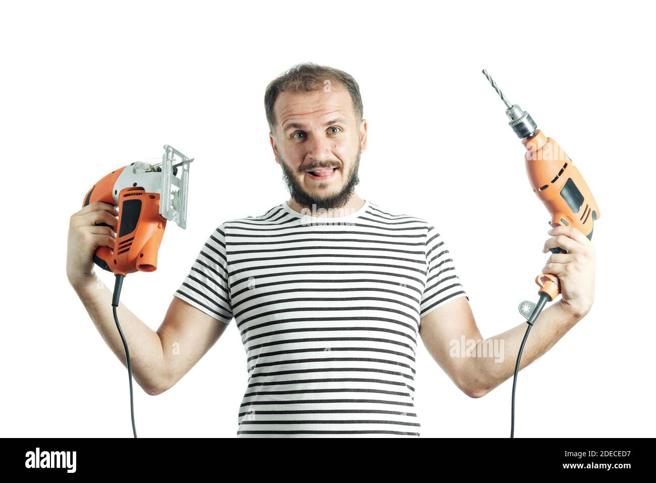 Un homme stupide tient une perceuse et une scie électrique dans ses mains. Comment choisir un outil électrique Banque D'Images