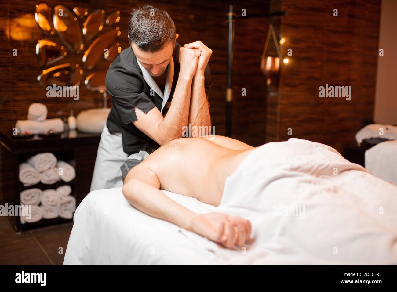 Masseur professionnel effectuant un massage profond à un client masculin au salon Spa, massage des épaules Banque D'Images