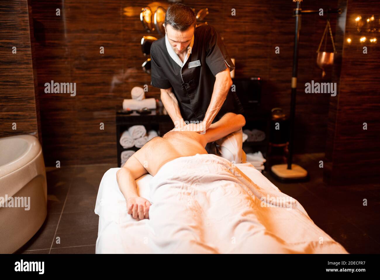 Masseur professionnel effectuant un massage profond à un client masculin au salon Spa, massage des épaules Banque D'Images