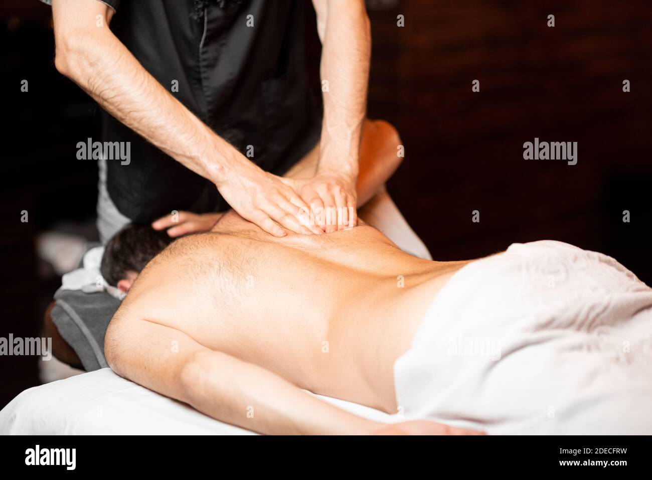 Masseur professionnel effectuant un massage profond à un client masculin au salon Spa, massage des épaules Banque D'Images