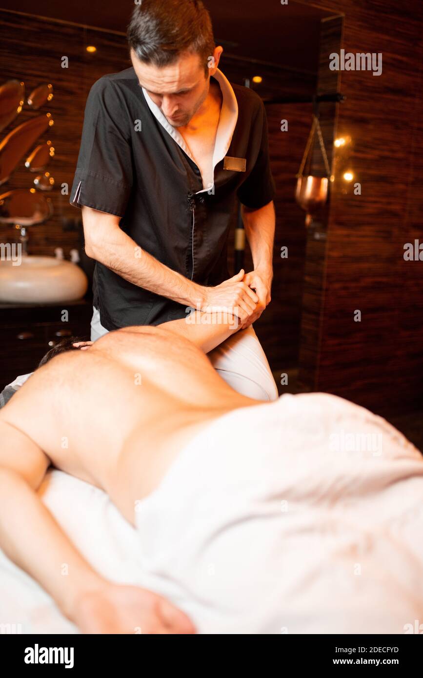 Masseur professionnel effectuant un massage profond à un client masculin au salon Spa, massage des épaules Banque D'Images