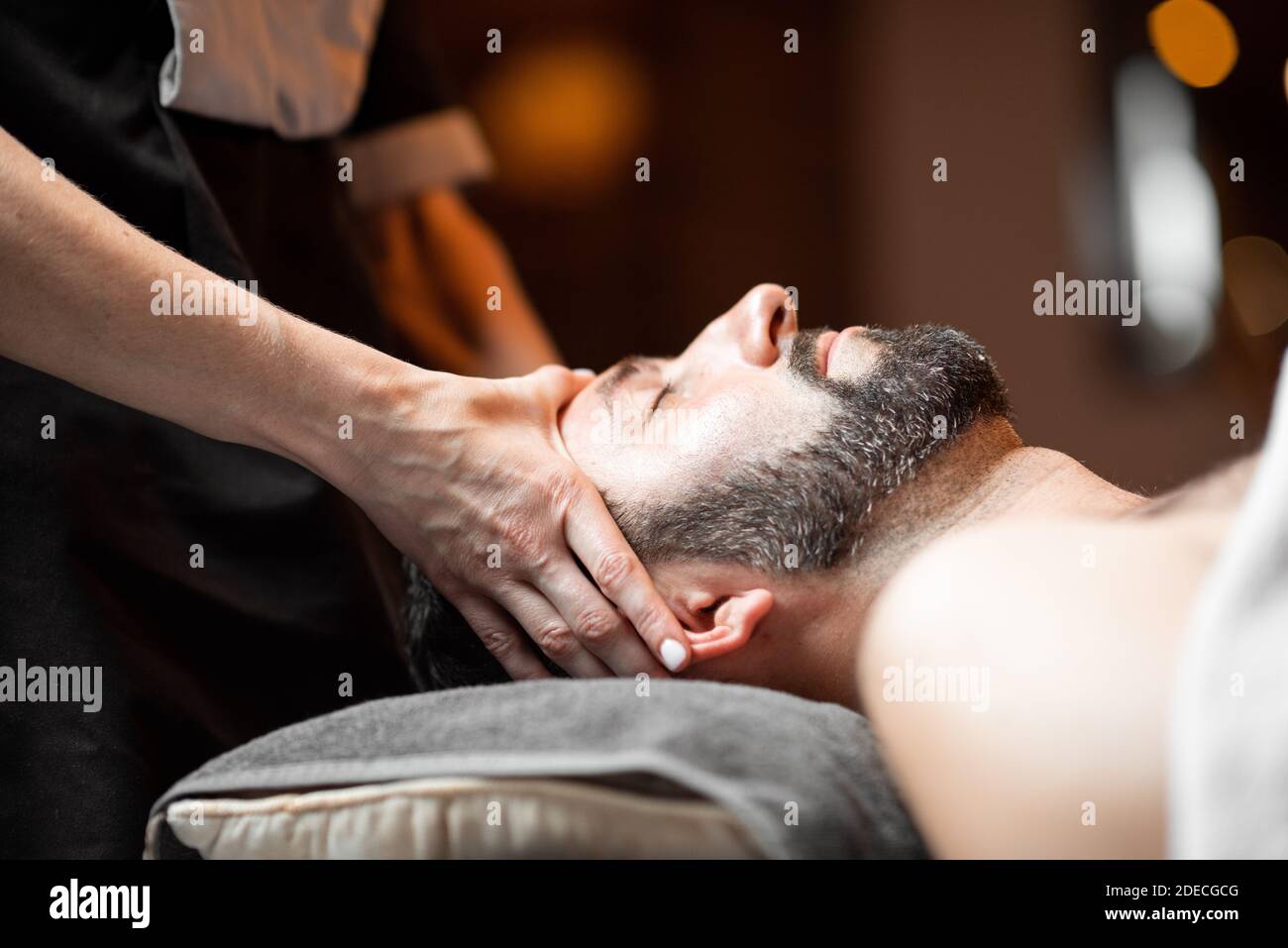 Homme barbu recevant un massage du visage, se détendre au spa salon, en gros plan Banque D'Images