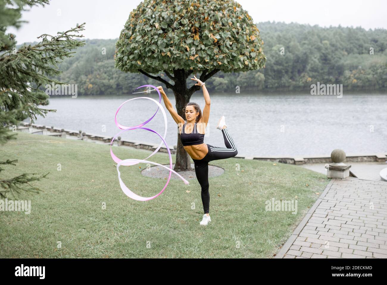 Femme sportive pratiquant la gymnastique rythmique avec un ruban en plein air Banque D'Images