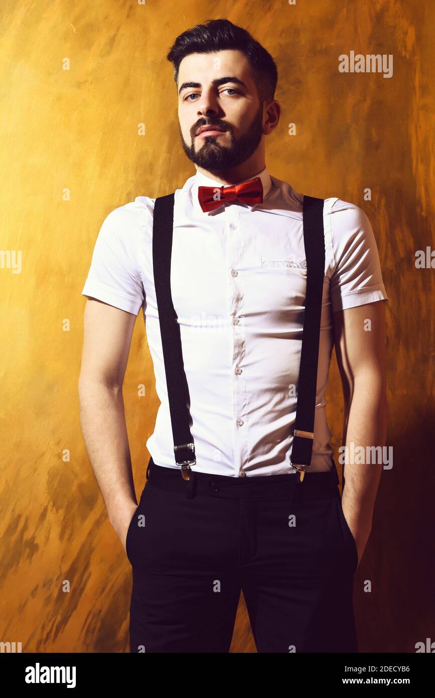 homme barbu, barbe longue, hipster caucasien brutal avec moustache en  chemise blanche et bretelles noeud-cravate posant avec un visage sérieux  sur fond brun de mur de studio Photo Stock - Alamy