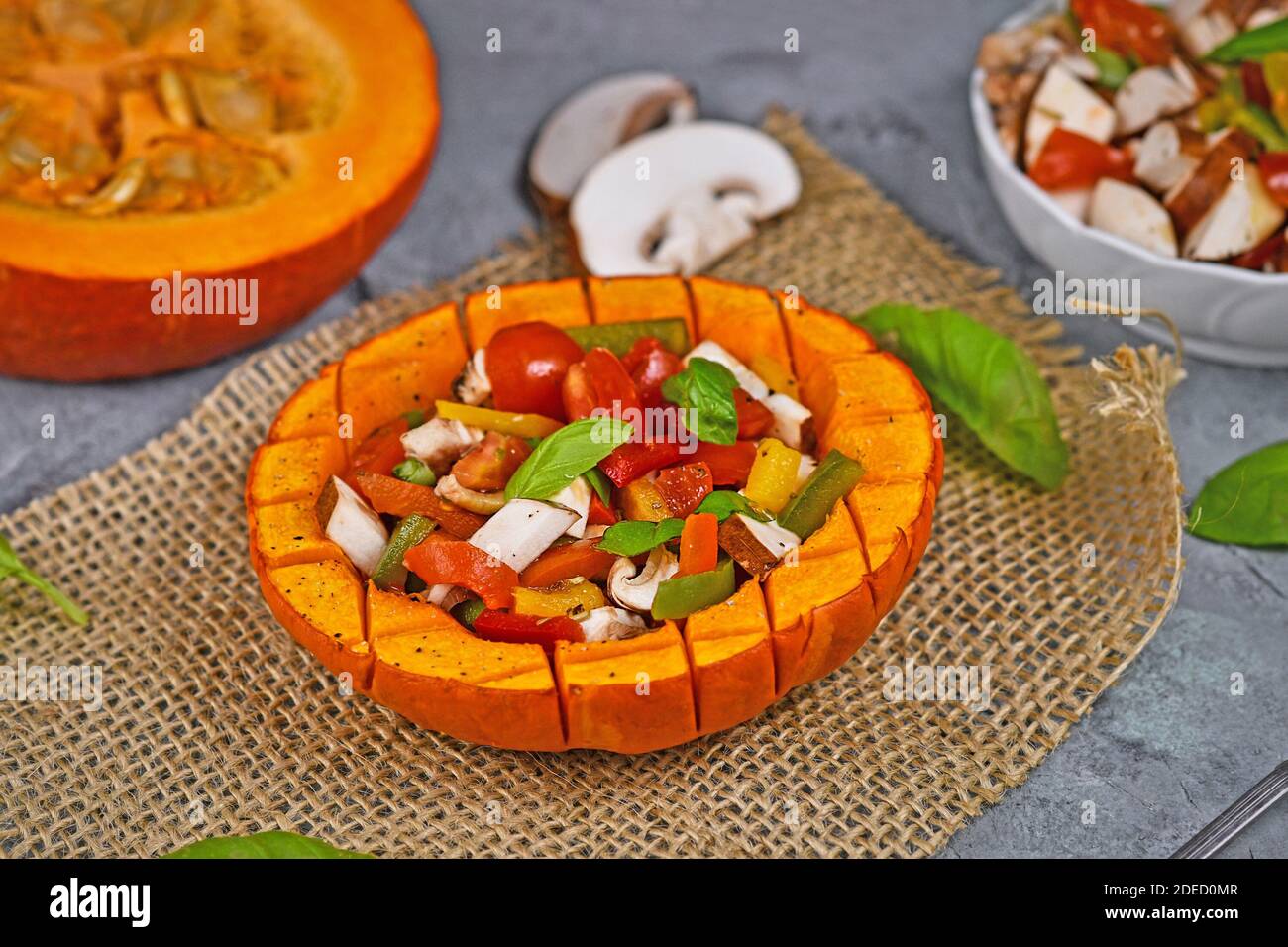 Légumes de courge rouge kuri cuits au four végétalien, au poivron, aux tomates et aux champignons entourés d'ingrédients Banque D'Images