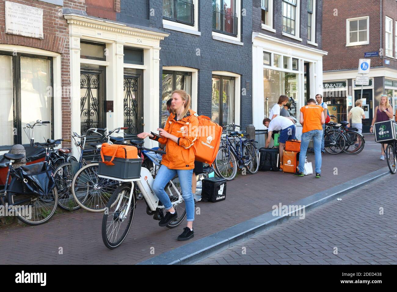 AMSTERDAM, Pays-Bas - 9 juillet 2017 : Uber mange, et Deliveroo Thuisbezorgd couriers alimentaire attendre à Amsterdam, Pays-Bas. Location livraison de nourriture est po Banque D'Images