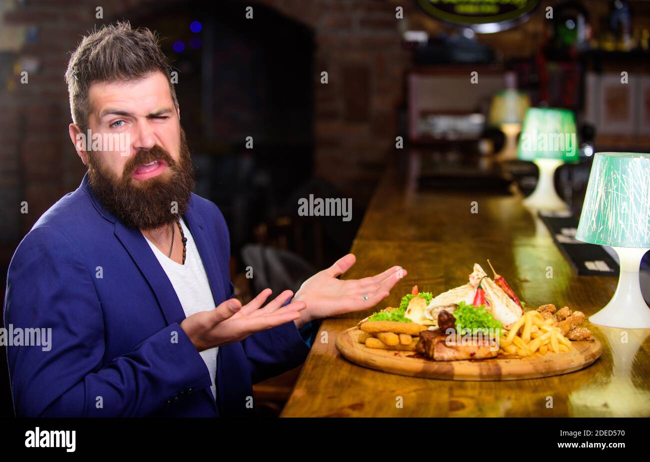 L'homme a reçu de pommes de terre frites repas avec les bâtonnets de poisson viande. Délicieux repas. Profitez de repas. Tricher repas. Hipster faim manger pub aliments frits. Restaurant client. Costume officiel Hipster s'asseoir au comptoir du bar. Banque D'Images