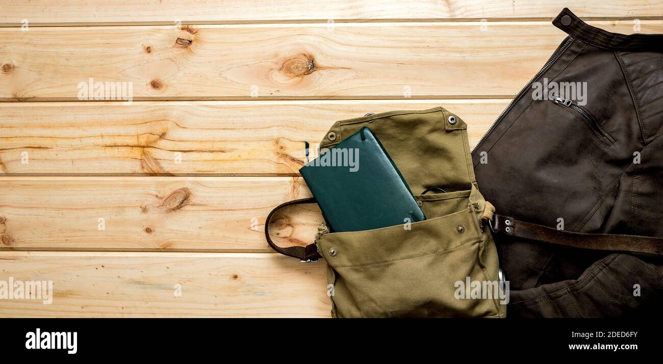 Veste et sac à bandoulière avec ordinateur portable prêt à voyager fond panoramique en bois avec espace pour le texte Banque D'Images