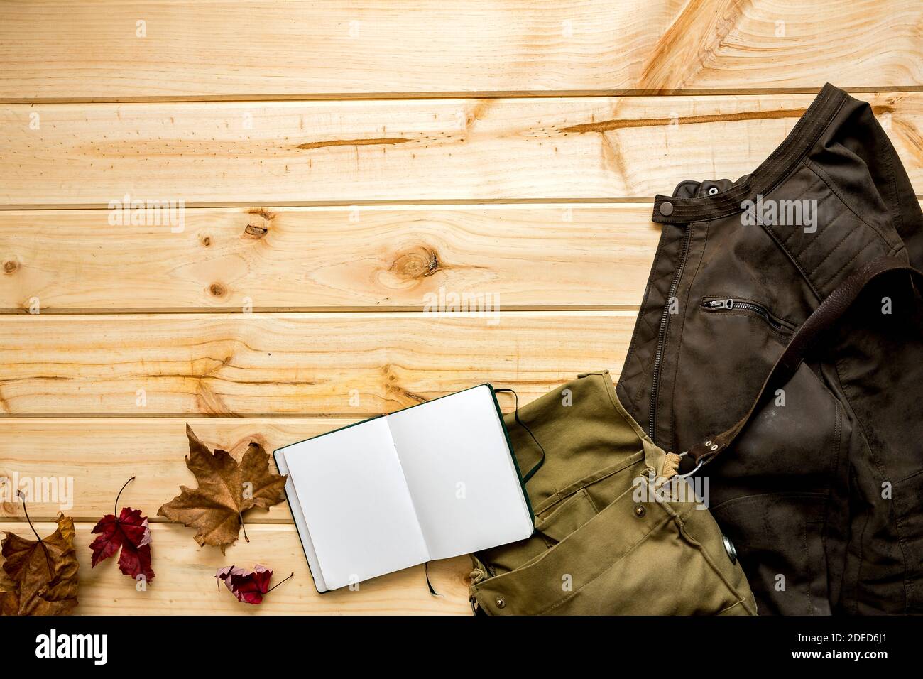 Veste et sac à bandoulière avec carnet et feuilles prêtes à l'emploi voyagez sur un arrière-plan en bois d'automne avec de l'espace pour le texte Banque D'Images
