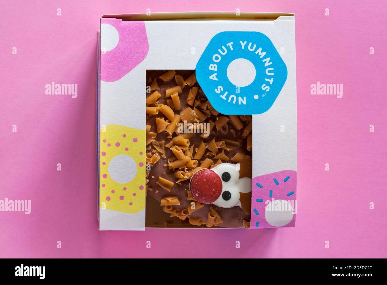 Rudolph le Donut à nez rouge dans une boîte fraîche de la boulangerie Chez Marks & Spencer, isolé sur fond rose - renne Donut pour Noël Banque D'Images