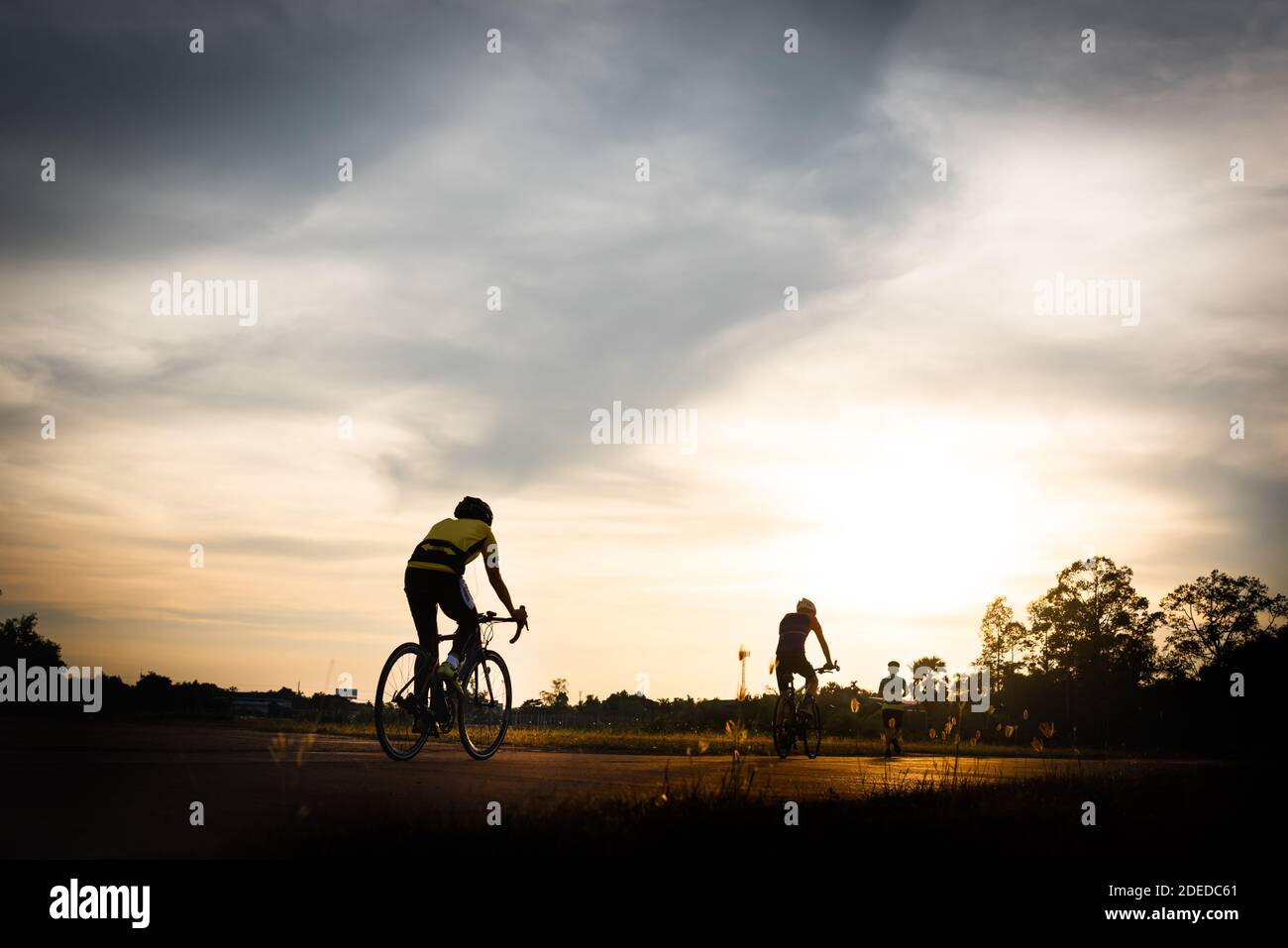 Le couple de cycliste qui fait du vélo de route au coucher du soleil, image de silhouette. Banque D'Images