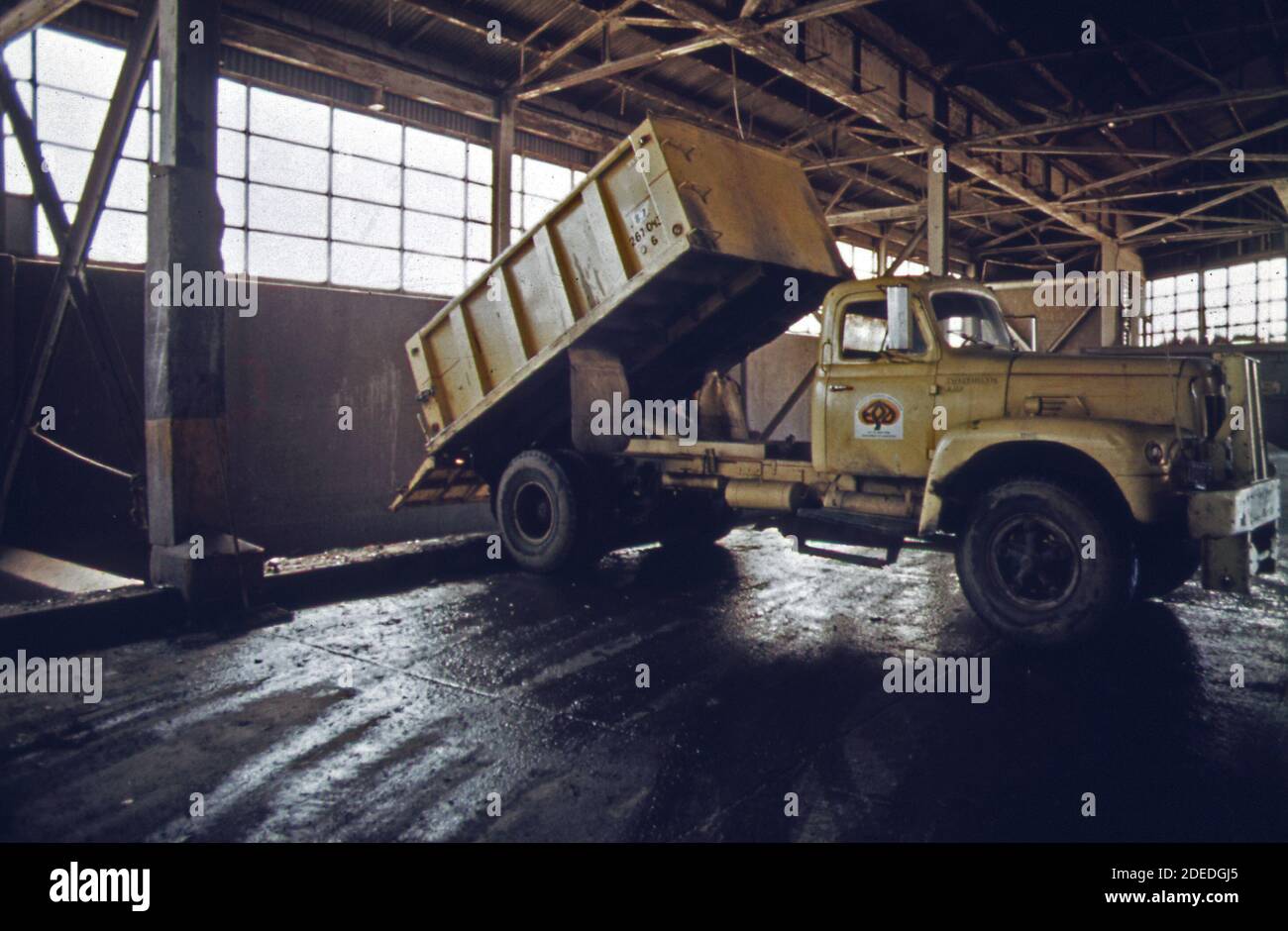Photo des années 1970 - (1973) - camion à la 91e rue la station de transfert maritime vide les ordures dans la barge pour un voyage vers le bas La rivière East jusqu'au site d'enfouissement de Staten Island Banque D'Images