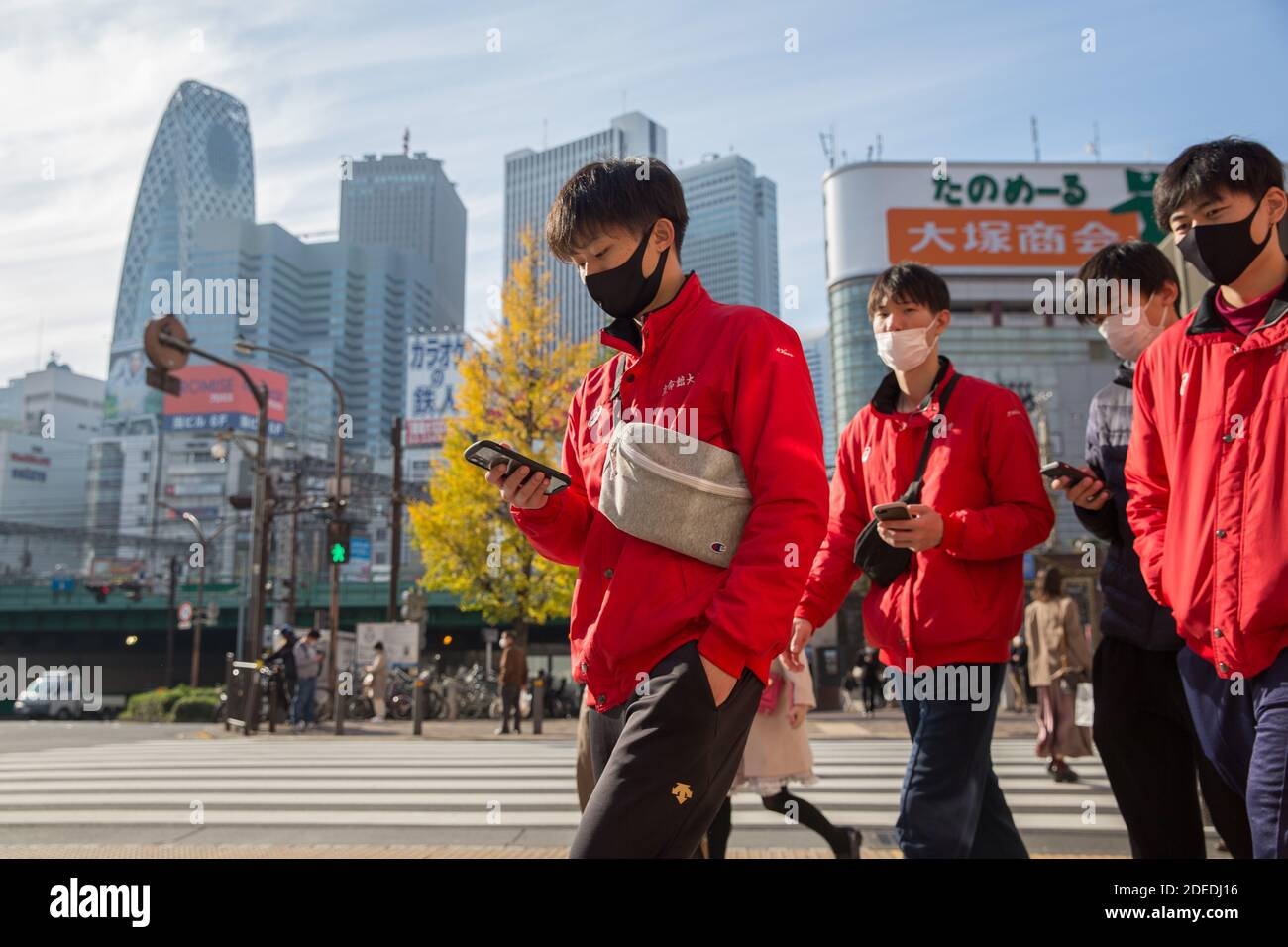 Un groupe de jeunes hommes portant un masque facial comme mesure préventive contre les promenades de Covid19 en face de Shinjuku Skyline à Tokyo. Banque D'Images